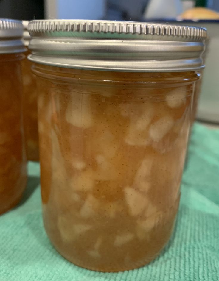 two jars filled with food sitting on top of a green tablecloth covered table cloth