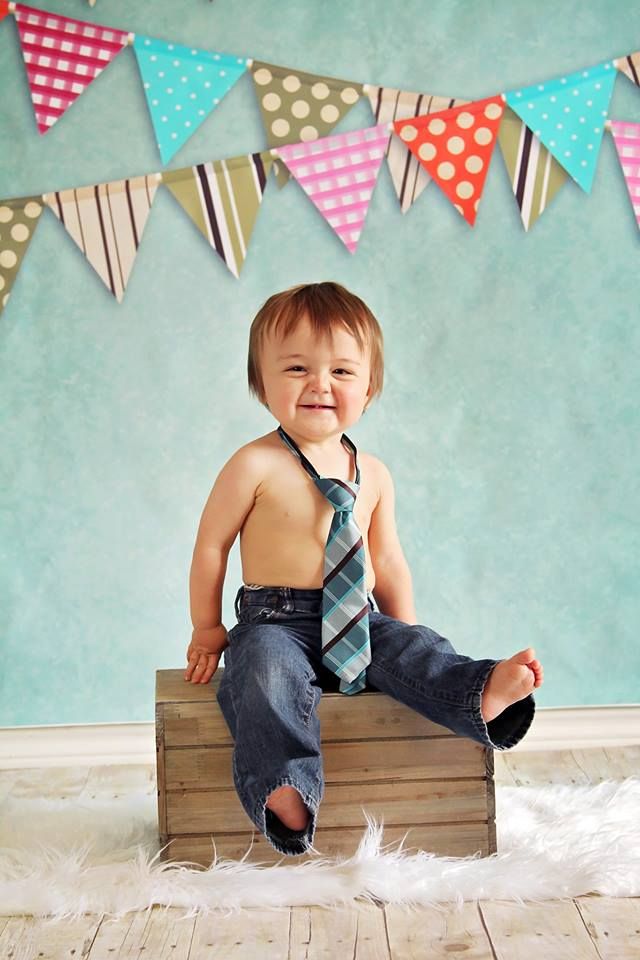 a little boy sitting on top of a wooden crate wearing a neck tie and jeans