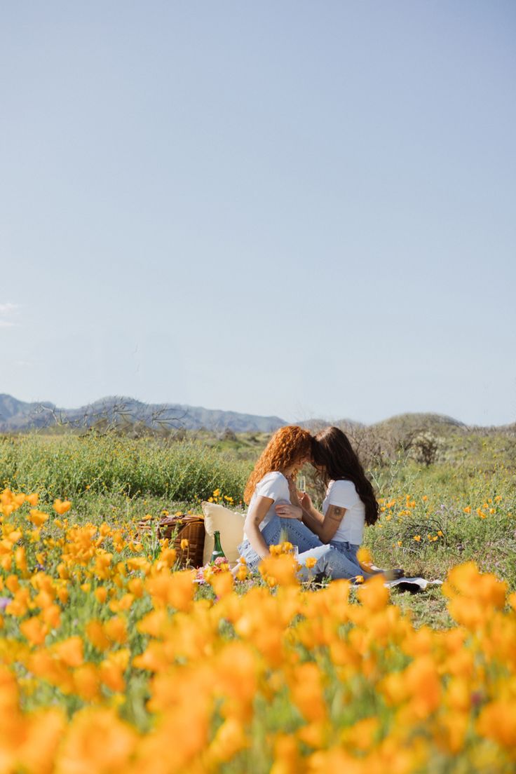 two people sitting in the middle of a field with yellow flowers