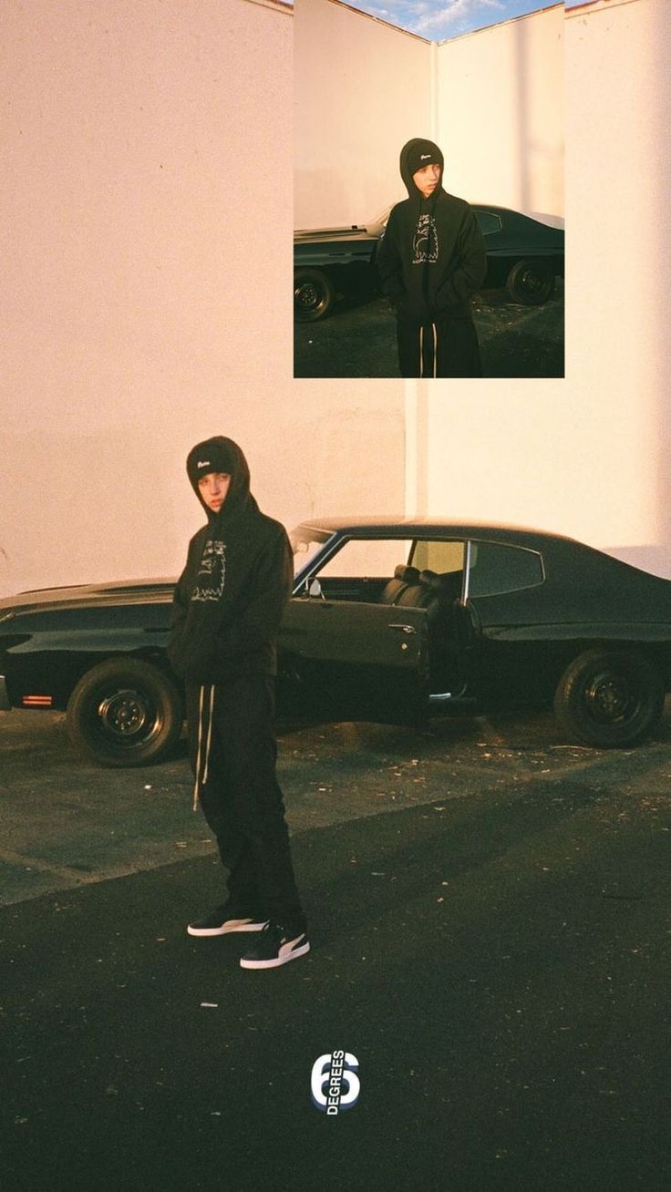 a man standing in front of a black car on the street next to a white building