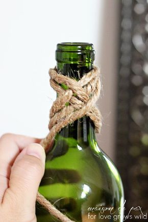 a hand holding a rope wrapped around a green bottle