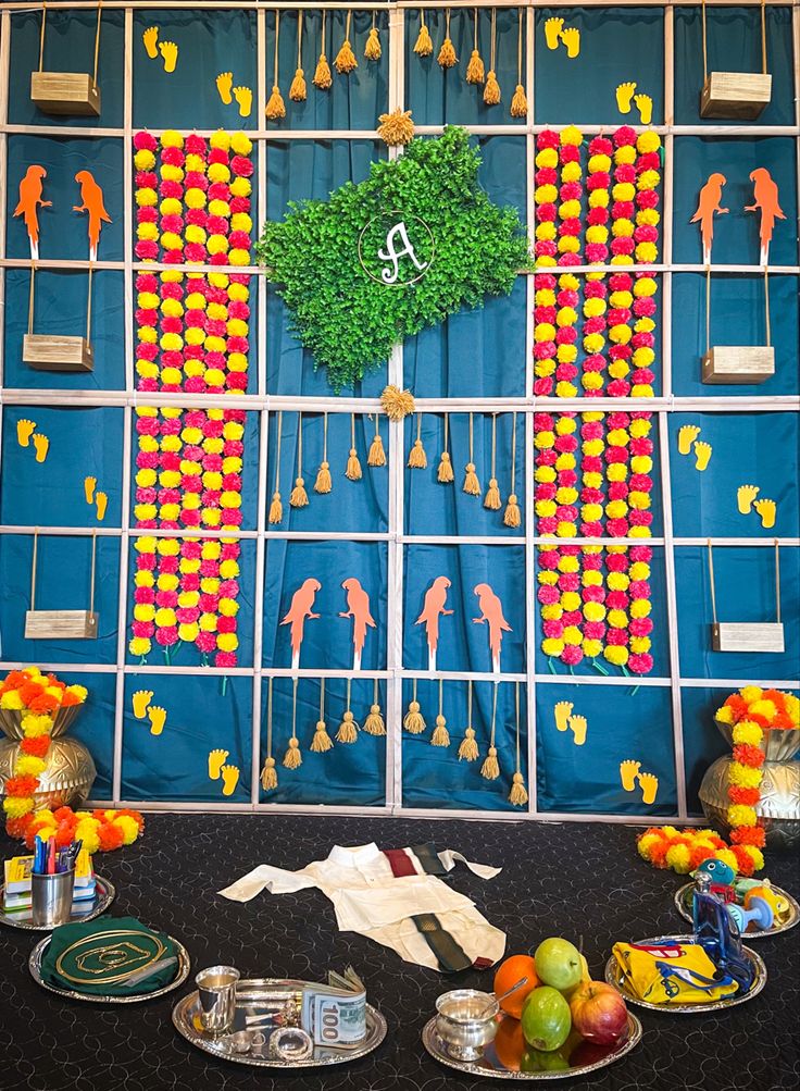 a table topped with plates and bowls filled with fruit next to a wall covered in decorations