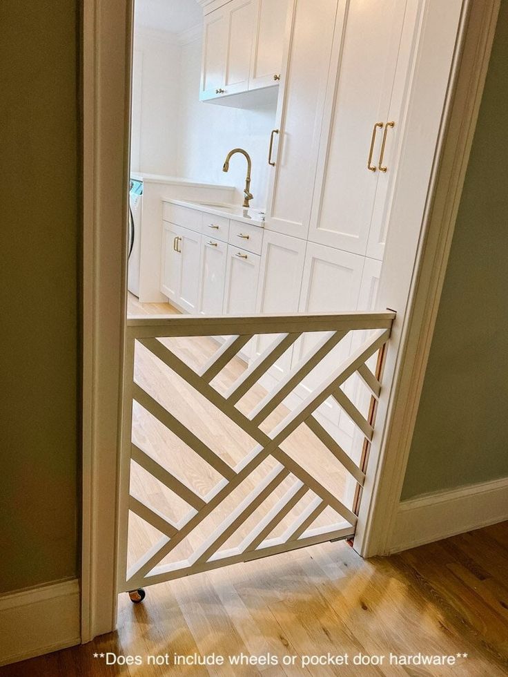 an open door leading to a kitchen with white cabinets and wood floors in the background