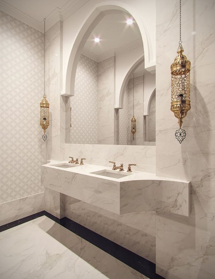 a bathroom with two sinks and an arched doorway in the wall behind them is white marble