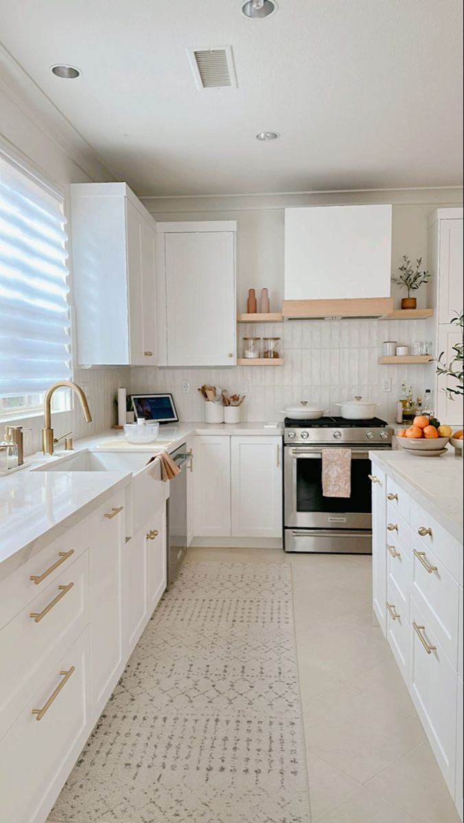 a kitchen with white cabinets and gold hardware on the handles, drawers, and counters