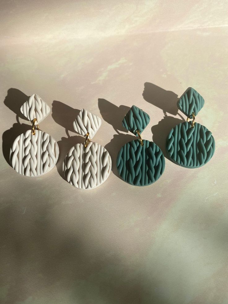 three pairs of blue and white earrings hanging from a line on a table with light colored background