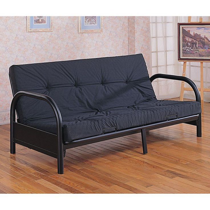 a black futon couch sitting on top of a hard wood floor next to a window