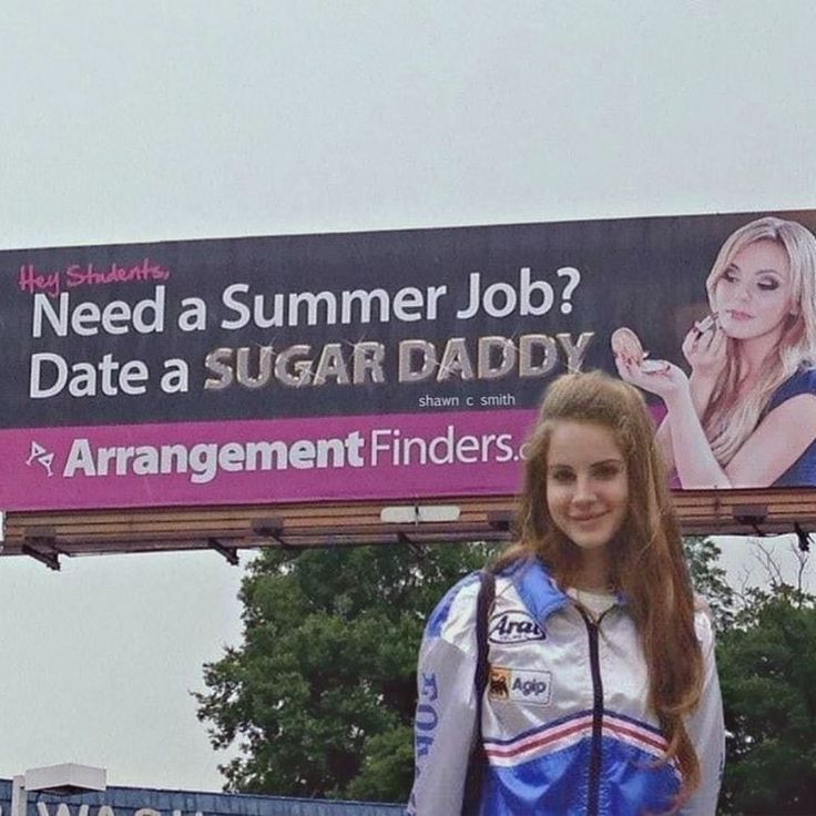 a woman standing in front of a billboard with her name on it and an advertisement behind her