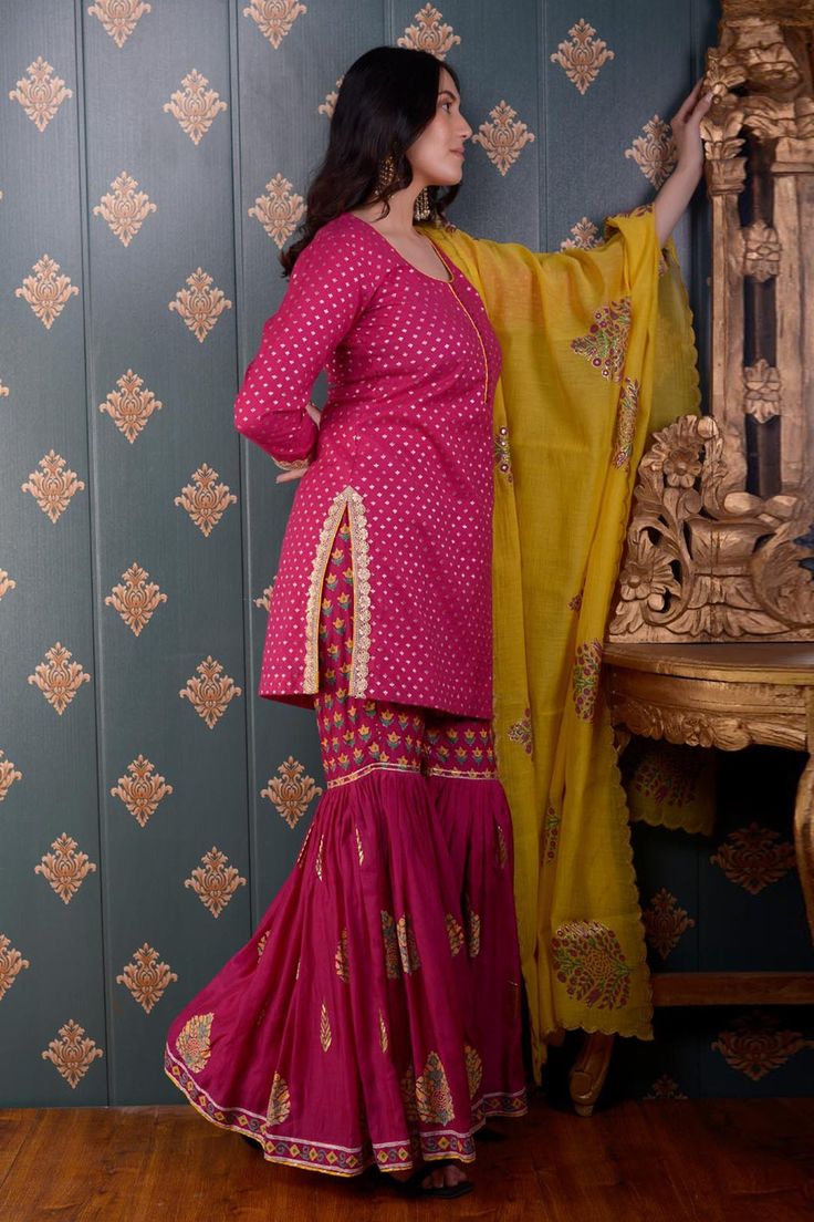 Magenta kurta with foil print motifs and lace trim on the sleeve hems. Comes with sharara and yellow chanderi dupatta.
Component: 3
Pattern: Print
Type Of Work: Foil Print
Neckline: Round
Sleeve Type: Three Quarter
Fabric: Kurta: Banarasi Chanderi, Sharara: Cotton Satin and Dupatta: Chanderi
Color: Magenta
Other Details: 
Printed dupatta with scalloped border
Side slits
Potli button front detailing
Occasion: Wedding - Aza Fashions Semi-stitched Banarasi Silk Sharara With Dabka Work, Festive Kundan Sharara With Dabka Details, Bollywood Style Unstitched Sharara For Navratri, Navratri Semi-stitched Cutdana Sharara, Diwali Sharara With Dabka Work And Traditional Drape, Unstitched Sharara With Dori Work For Diwali, Unstitched Sharara For Designer Wear During Navratri, Diwali Sharara With Dori Work, Kundan Sharara With Dabka For Festivals