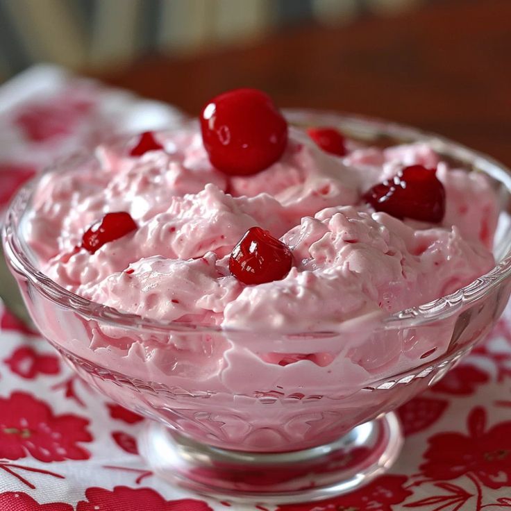 a bowl filled with ice cream and cherries on top of a red table cloth