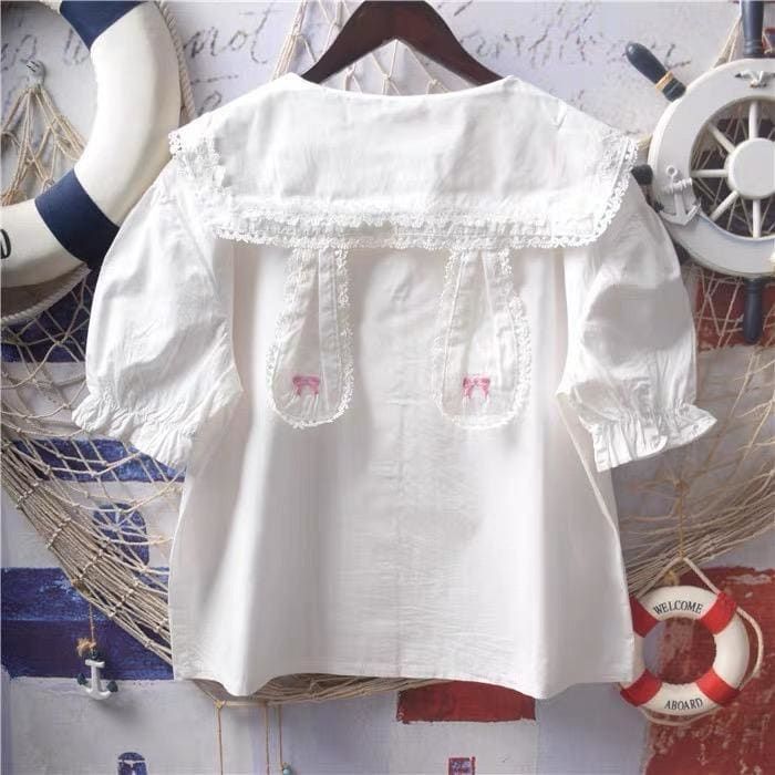 White Bunny Collar Kawaii Lolita Shirt with Pan Collar and Lace Bow Embroidery, available with short sleeves and long sleeves   ONE SIZE Bust: 104cm/41" Length: 56cm/22"     Material: COTTON, Polyester Kawaii Collared Shirt, White Harajuku Style Tops For Summer, Harajuku Style White Summer Top, Harajuku White Summer Top, White Harajuku Style Summer Tops, Harajuku Tops With Ruffles, Harajuku Style Ruffled Tops, White Embroidered Top With Collar, Spring Kawaii Top With Doll Collar