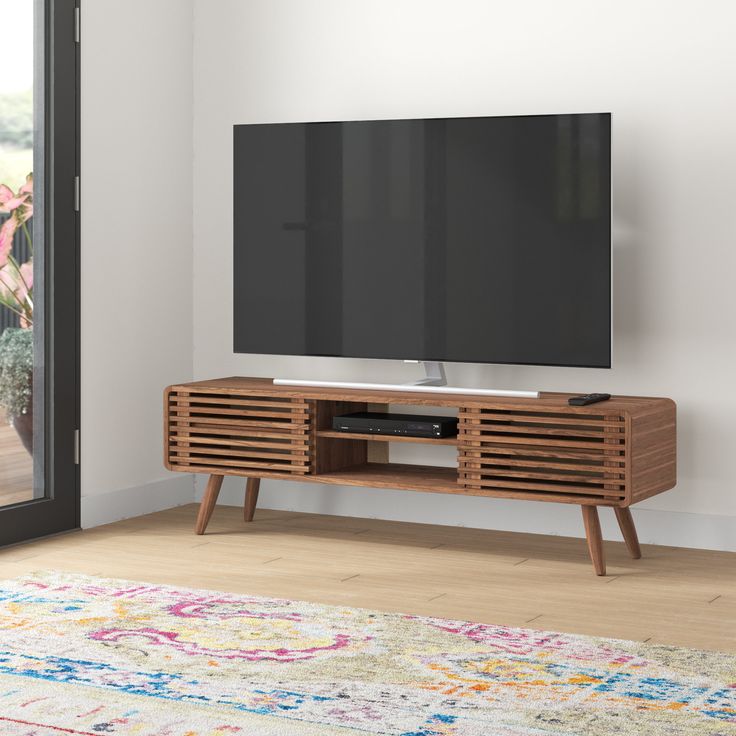 a flat screen tv sitting on top of a wooden entertainment center next to a sliding glass door