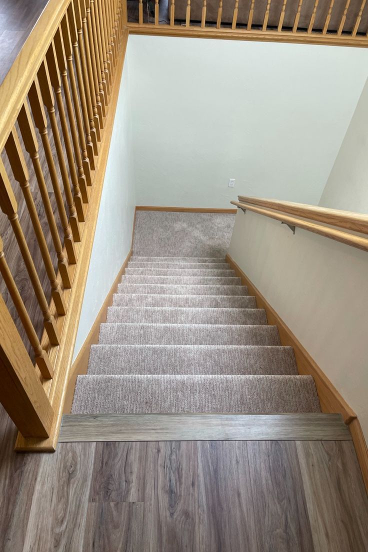 an empty staircase with carpet and wooden handrails