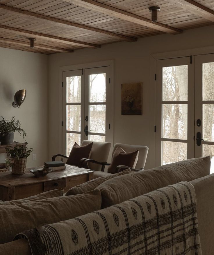 a living room filled with furniture and windows covered in wood planks on the ceiling