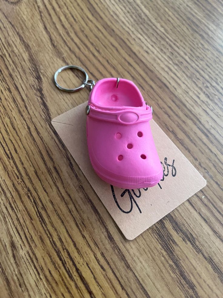 a pink shoe keychain sitting on top of a wooden table