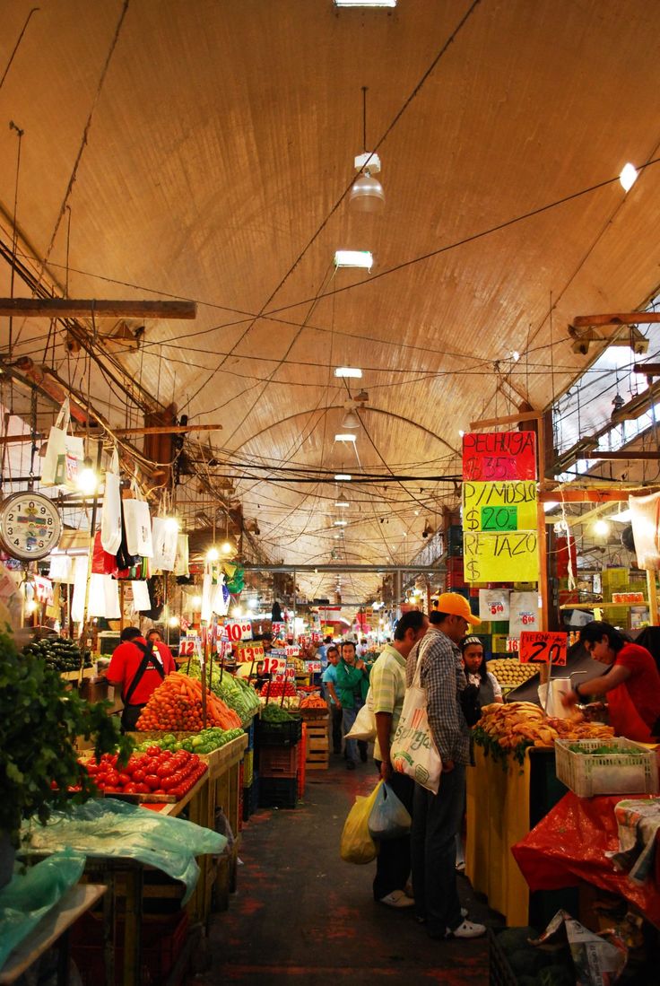 an indoor market with people shopping for produce