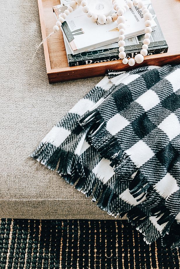 a black and white checkered blanket sitting on top of a couch next to a wooden tray