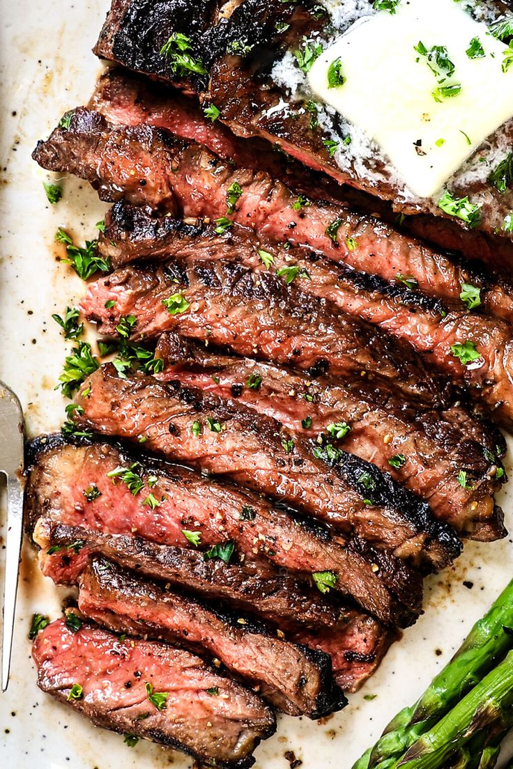 grilled steak and asparagus on a plate with butter, parmesan and sauce