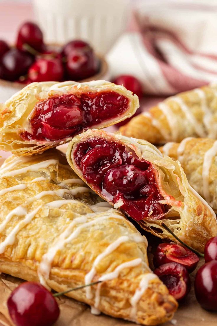 cranberry turnovers with icing and cherries on a wooden cutting board