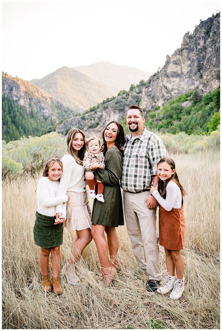 a family standing in tall grass with mountains in the backgrouds behind them