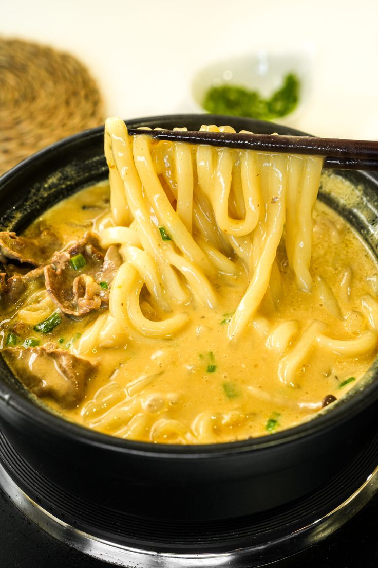 a black bowl filled with noodles and meat