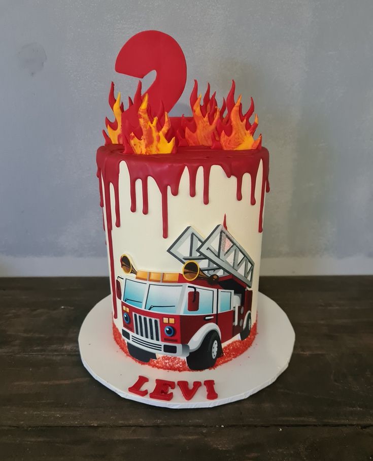 a birthday cake with a firetruck and number two on the top is painted red