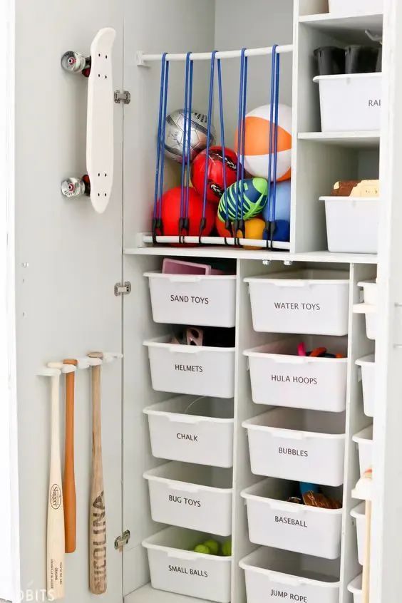 a white closet filled with lots of bins and baskets next to a baseball bat