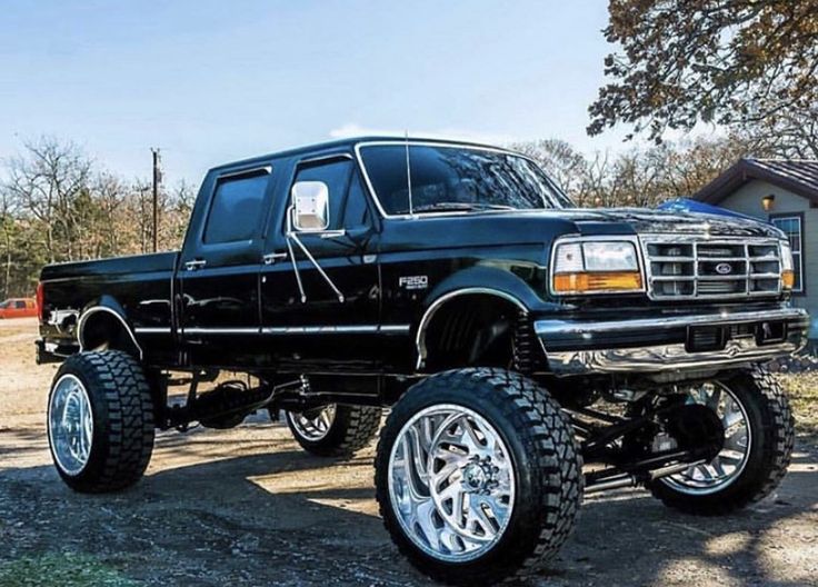 a large black truck parked on top of a dirt field