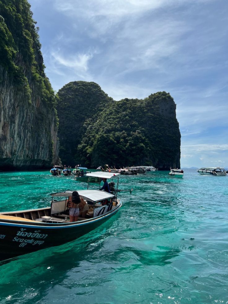 two boats in the water with people on them near some rocks and cliffs that look like they're floating