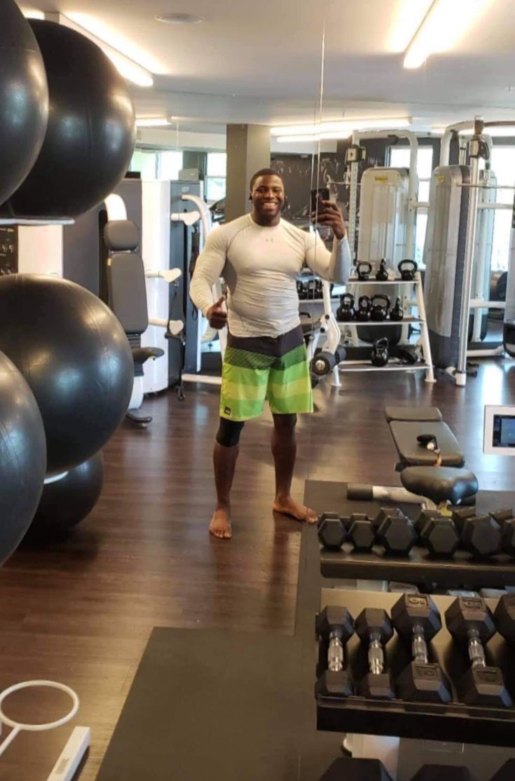 a man taking a selfie in the gym with his cell phone and dumbbells