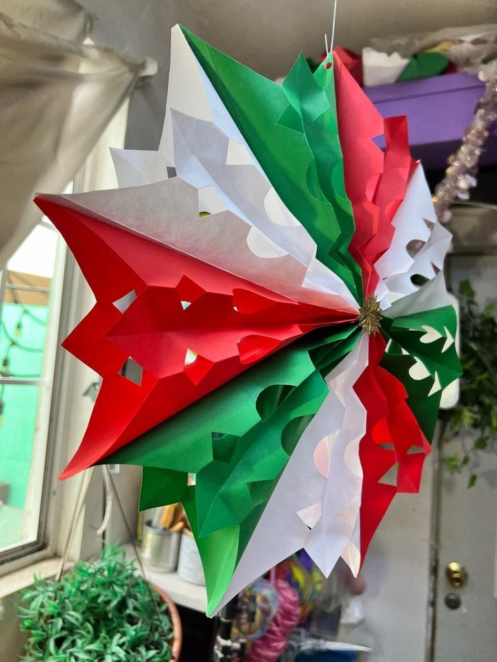 an origami umbrella hanging from the ceiling in front of a potted plant