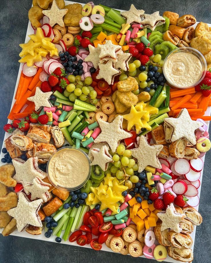 a platter filled with fruit, crackers and dips