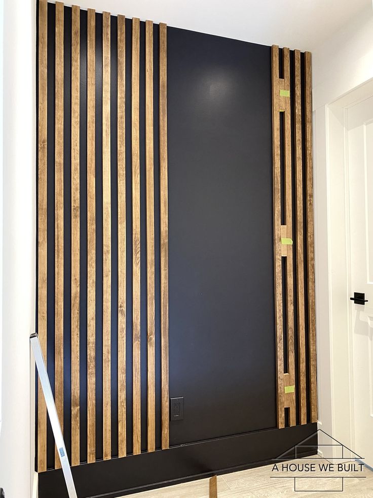 a room with black walls and wooden slats on the wall, along with a white door