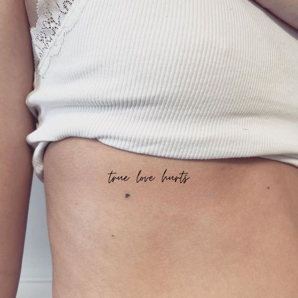 a woman's stomach with the words through the heart tattooed on her side ribcage