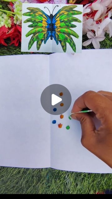 a person is drawing with colored pencils on top of an open book and flowers in the background