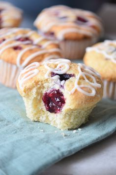 blueberry muffins with white frosting and fresh berries in the middle are shown