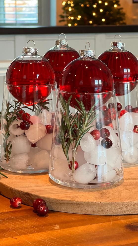 three glass vases filled with red and white ornaments on top of a wooden table