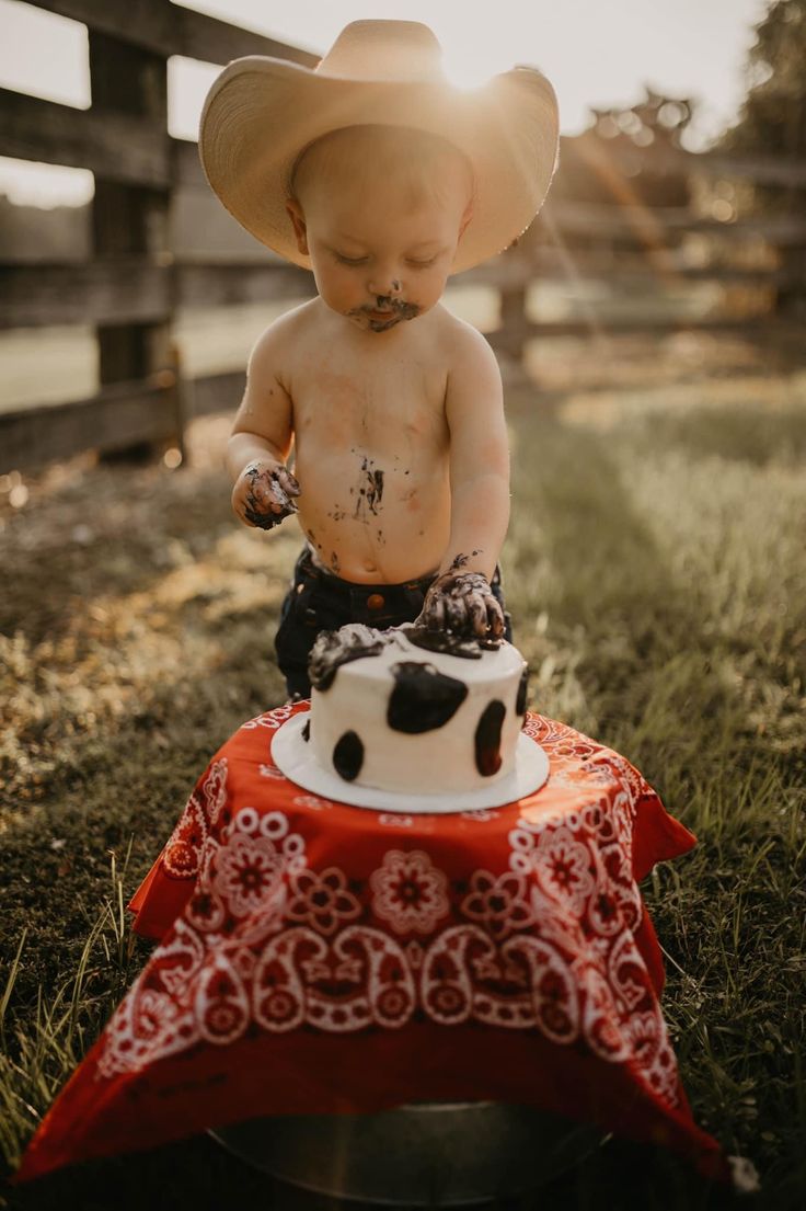 a small child wearing a cowboy hat sitting on top of a cake