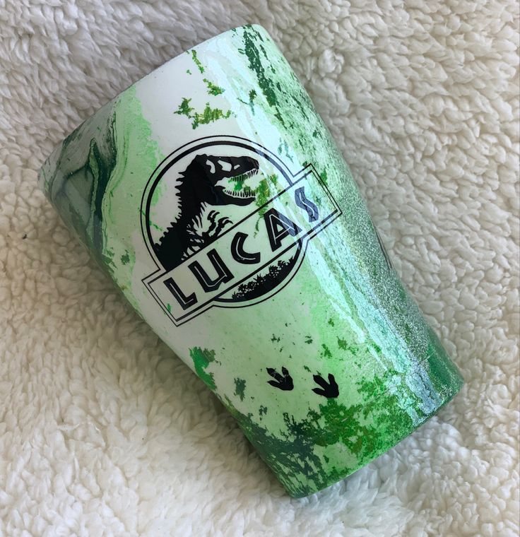 a close up of a green and white cup on a blanket with the word asu printed on it