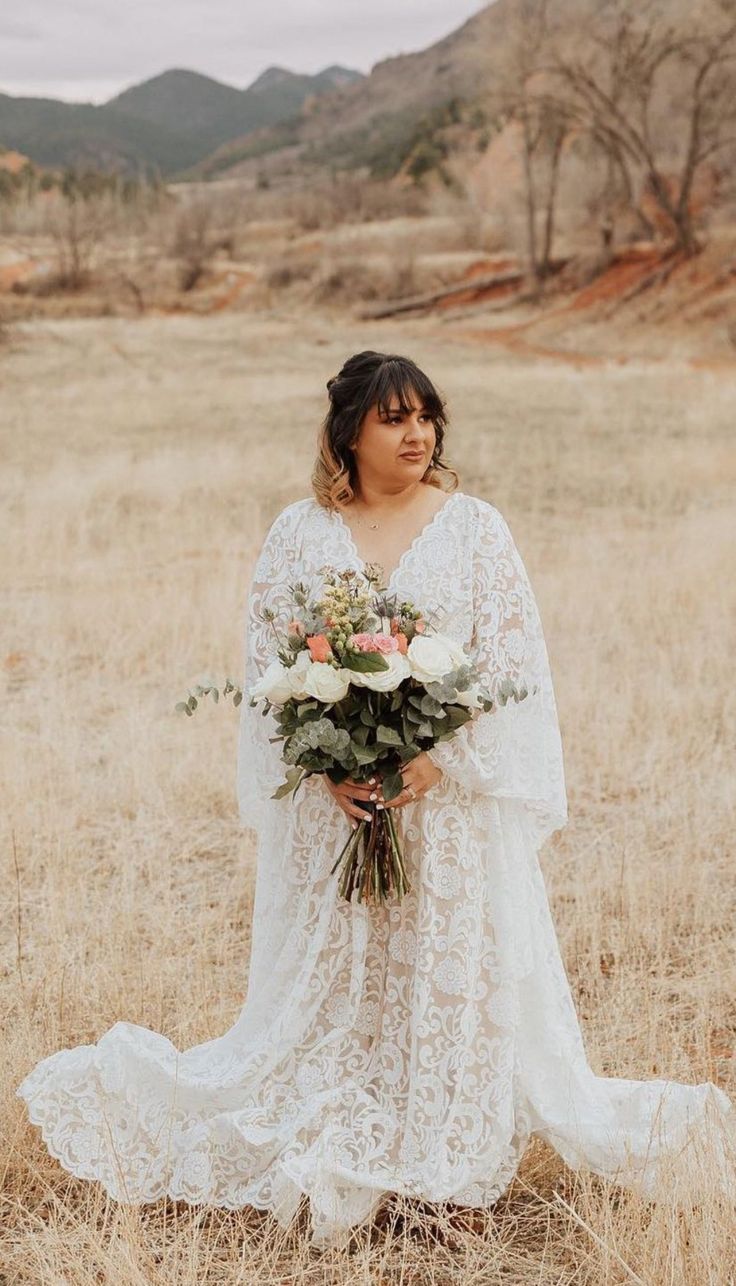 a woman standing in a field holding a bouquet of flowers