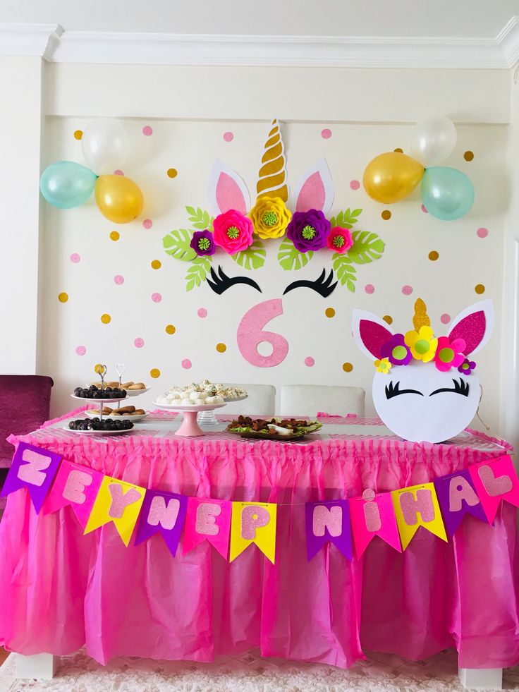 a table topped with lots of food next to a unicorn wallpapered on the wall