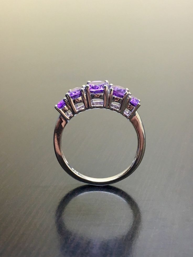 DeKara Designs Silver Metal- 14K White Gold, .583. Stones- 5 Natural Oval Amethyst, Center is 6.9 x 5 MM, Next To Center 6 x 4.3 MM, and last two are 4.9 x 3 MM. Size- Size- PLEASE ALLOW 5-7 WORKING DAYS FOR US TO SHIP OUT YOUR RING IN YOUR SPECIFIC SIZE AFTER TRANSACTION HAS BEEN COMPLETED PLEASE SPECIFY SIZE UPON CHECKOUT! An alternative to a diamond ring, here is timeless beautiful handmade 5 stone amethyst engagement ring. All the amethyst are fiery and set between 4 prongs. Very affordable Purple Sapphire Ring With Brilliant Cut For Anniversary, Purple Sapphire Ring With Brilliant Cut, Anniversary Amethyst Ring With Brilliant Cut, Purple Brilliant Cut Rings For Promise, Fine Jewelry Purple Rings With Brilliant Cut, Purple Fine Jewelry With Vvs Clarity, Luxury Lavender Amethyst Ring For Anniversary, Purple Brilliant Cut Ring, Fine Jewelry Amethyst Diamond Ring In Purple