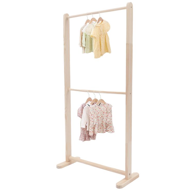 the wooden clothes rack is holding two baby's shirts and one child's shirt