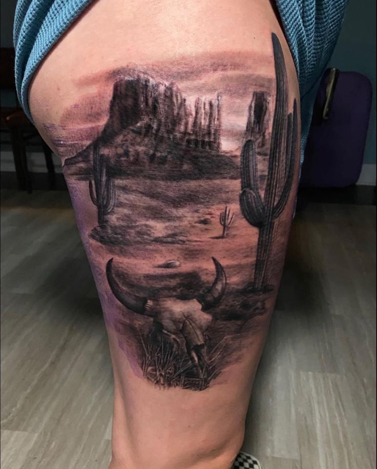 a woman's thigh with an image of a desert scene and cactuses on it