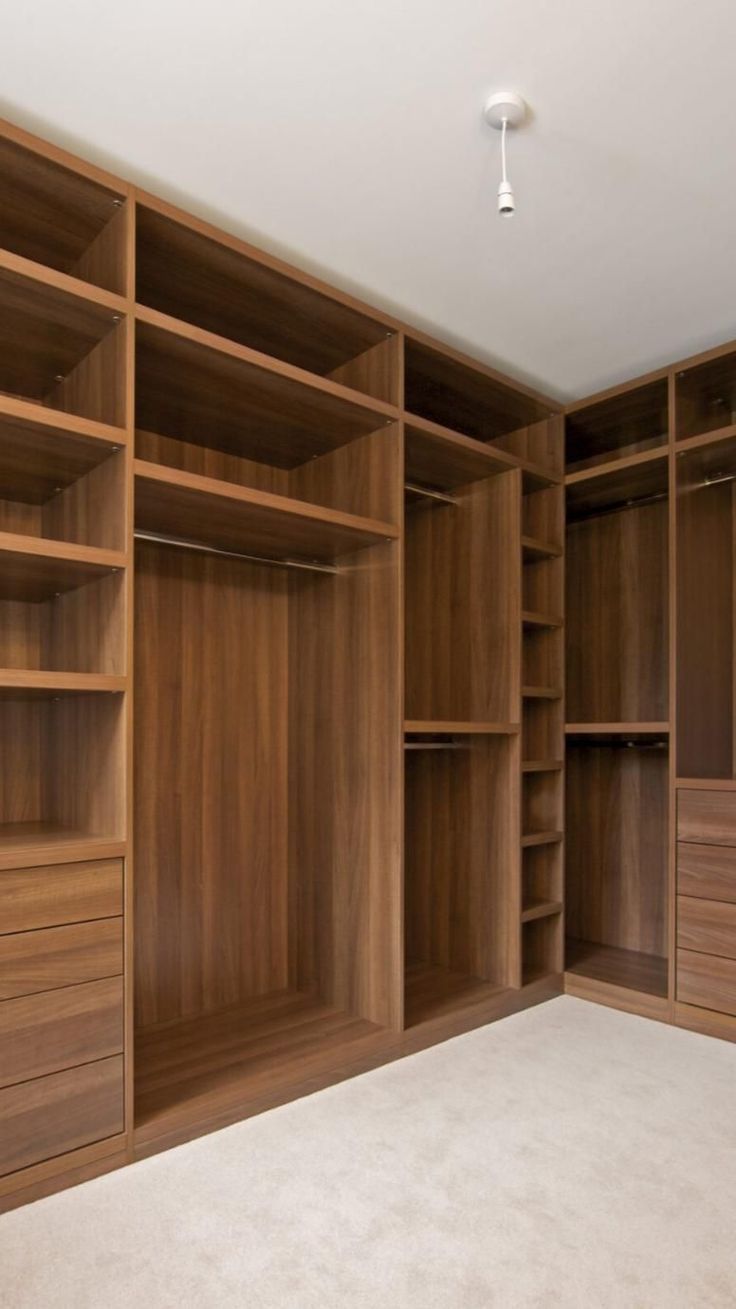 an empty walk - in closet with wooden shelves and drawers on the wall, carpeted floor