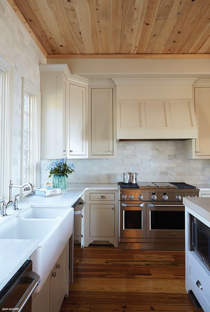 a kitchen with white cabinets and wood floors