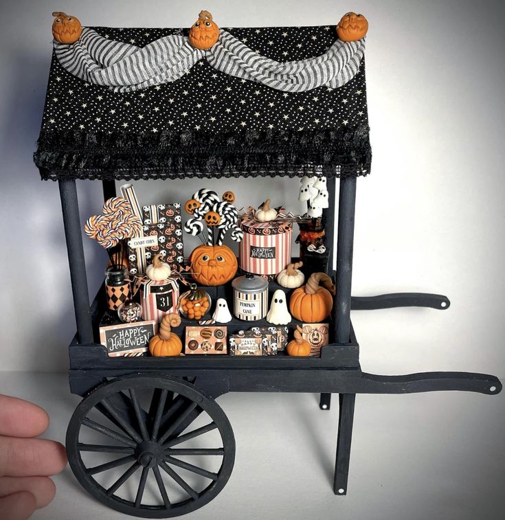 a miniature halloween display with pumpkins, candy and candies on a black cart