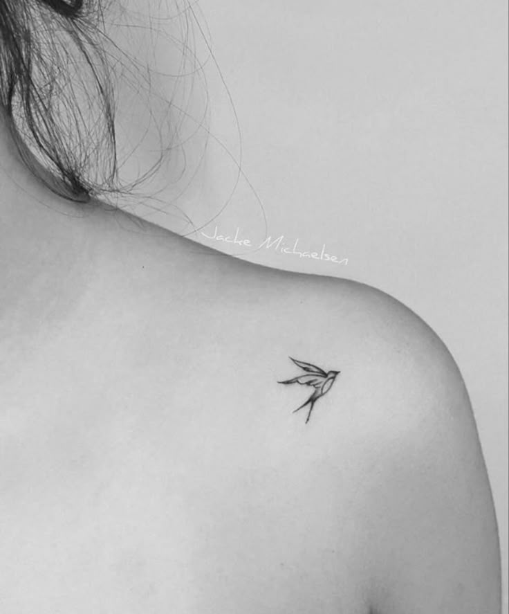 a black and white photo of a woman's shoulder with a small bird on it