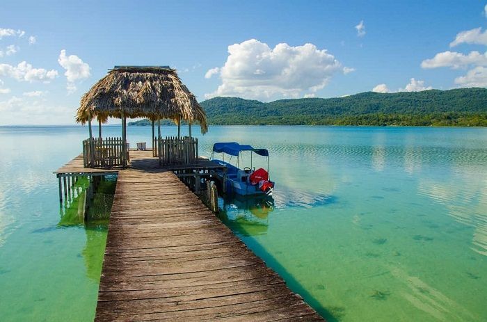 a boat is docked at the end of a wooden dock with a thatched roof