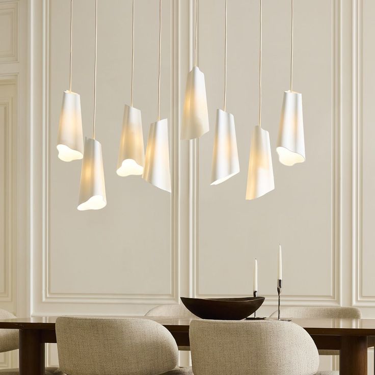 a dining room table with chairs and lights hanging from the ceiling